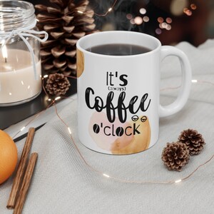 May include: White ceramic coffee mug with a black and white graphic that says "It's (always) Coffee o'clock" with watercolor-style brown and pink accents.