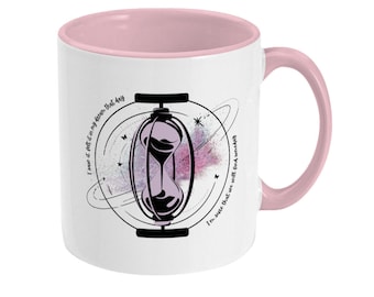 May include: White ceramic mug with a pink rim and handle. The mug features a black hourglass inside a circle with a galaxy background. The text around the hourglass reads "I knew it felt like it in my dream that day" and "I'm sure that we will find ourselves".