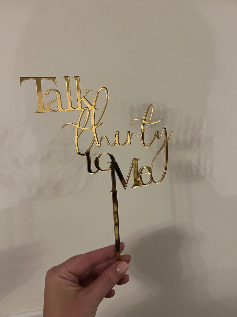 May include: Gold cake topper with the text "Talk Thirty to Me" in a cursive font.