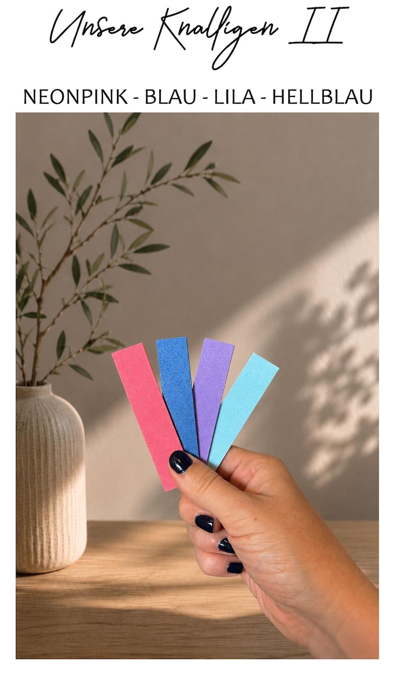 May include: Four rectangular strips of paper in neon pink, blue, purple, and light blue. The text at the top reads "Unsere Knalligen II" followed by "NEONPINK - BLAU - LILA - HELLBLAU". The strips are held together in a fan shape.