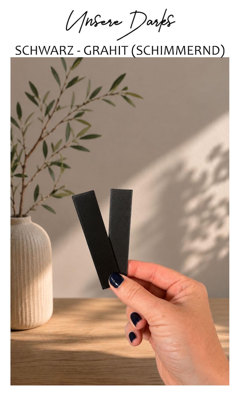 May include: Two rectangular black strips with a textured surface. The text "Unsere Darks" and "SCHWARZ - GRAHIT (SCHIMMERND)" appears at the top of the image. The strips have a matte finish and are held together in a vertical orientation.