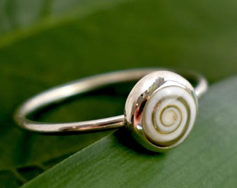 Può includere: Un anello d'argento con un'intarsio di conchiglia bianca con un motivo a spirale.