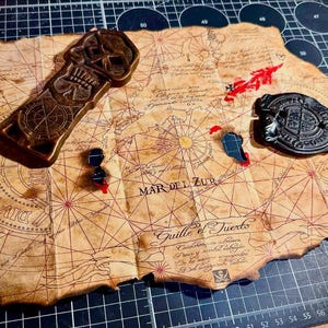 May include: Aged parchment map with red navigational lines and text, featuring a skull-shaped object, a compass-like design, and a black emblem. The map includes the text "MAR DEL ZUR" and "Guille el Tuerto".