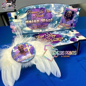 May include: A memorial bench with a photo of Helen West, featuring the text "Forever In Our Hearts" and "Just Keep Saying Morning". The bench has a celestial background with doves and a pair of white feather wings.
