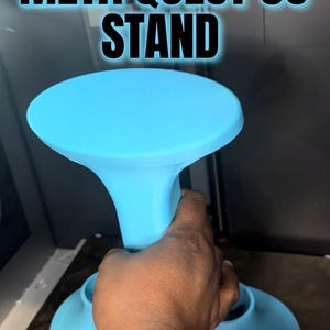 Puede incluir: Un soporte azul claro para Meta Quest 3S. El soporte tiene una parte superior redonda y una base acampanada. El texto "META QUEST 3S STAND" se muestra en letras blancas grandes y en negrita con un contorno azul.