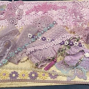 May include: A selection of lavender and lilac lace ribbons, trims, and embellishments. The assortment includes floral and butterfly designs, satin ribbon, and beaded trim. The items are arranged on a gold-coloured surface.