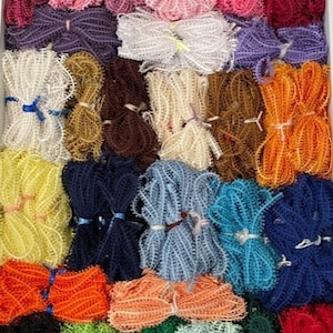 May include: A collection of 24 spools of colourful, textured, and patterned lace trim. The lace trim is arranged in rows and is ready to be used for crafting projects.