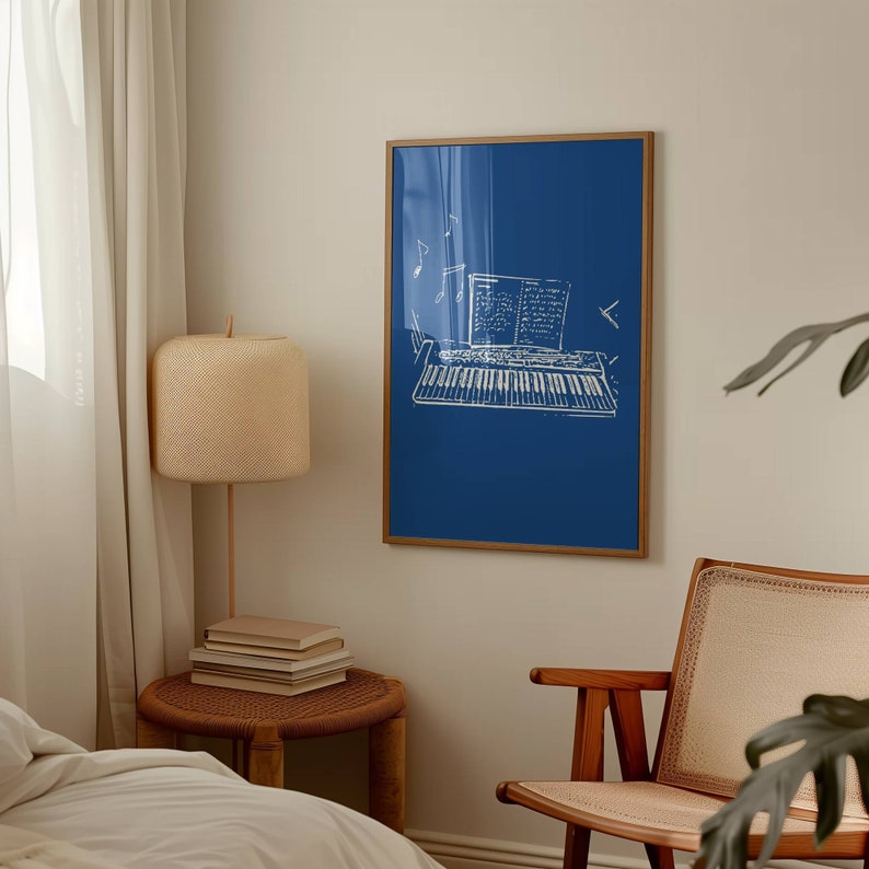 May include: A blue framed print with a white outline of a keyboard and sheet music. The print is hanging on a white wall above a wooden chair with a woven seat.