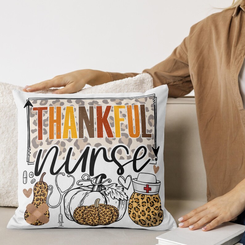 May include: White cushion with a leopard print background and the text "Thankful Nurse" in black and orange. The cushion features a stethoscope, a syringe, and three pumpkins with leopard print accents.