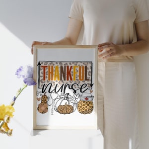 May include: A white framed print with the text "THANKFUL nurse" in brown, orange, and yellow letters. The print features a leopard print background with three pumpkins and a stethoscope.