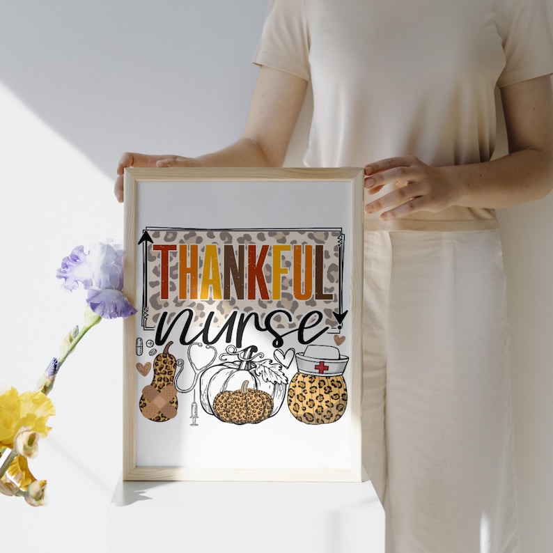 May include: A white framed print with the text "THANKFUL nurse" in brown, orange, and yellow letters. The print features a leopard print background with three pumpkins and a stethoscope.