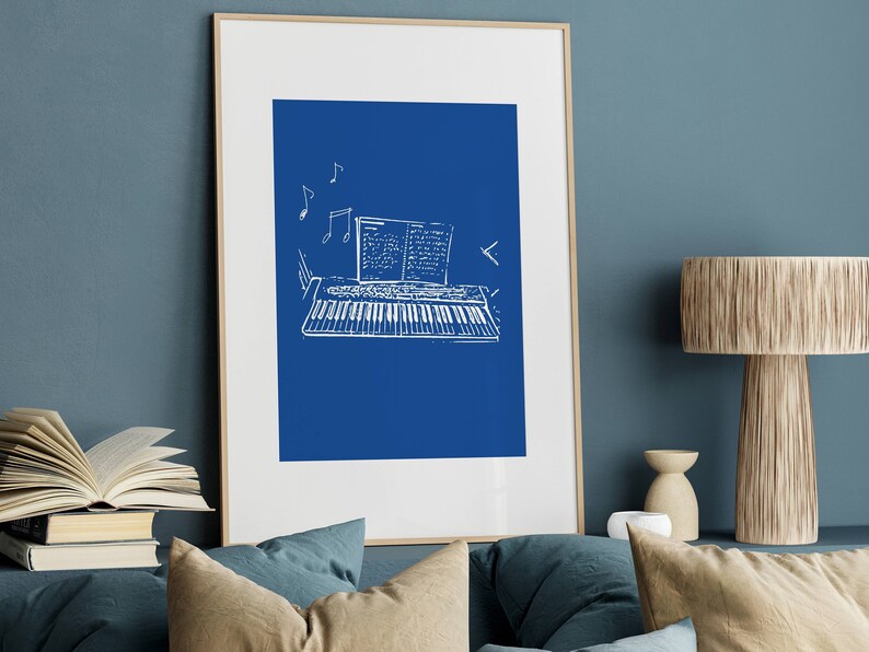 May include: A framed print of a white line drawing of a keyboard with sheet music on a blue background.