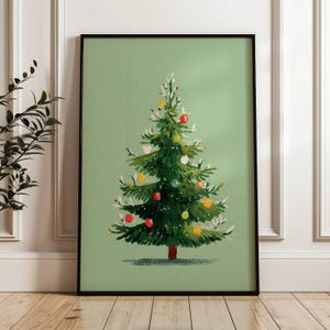 May include: A framed art print featuring a stylized Christmas tree illustration. The tree is green with colorful ornaments and a brown trunk, set against a light green background. The artwork is in a black frame.