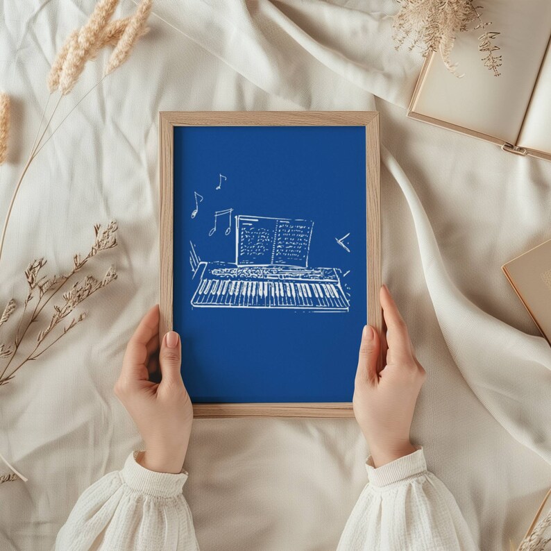 May include: A blue chalkboard with a white drawing of a keyboard and sheet music. The chalkboard is framed in wood and is being held by a person's hands.