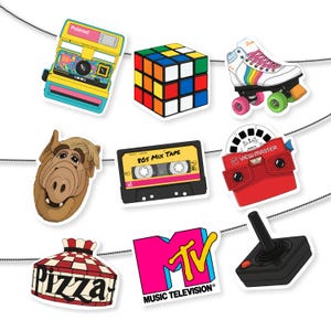 Op de afbeelding: Een verzameling stickers met een thema uit de jaren 80, waaronder een Polaroid-camera, Rubik's Cube, rolschaats, ALF-hoofd, cassettebandje met de tekst "80s Mix Tape", View-Master, pizzadoos, MTV-logo en een joystick.
