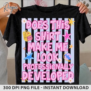 May include: A black t-shirt featuring a graphic with vertical black and light blue stripes. The text reads DOES THIS SHIRT MAKE ME LOOK PROFESSIONALLY DEVELOPED in pink letters. The design includes a yellow backpack, stars, and flowers.
