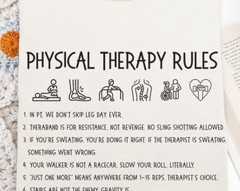 May include: Cream-colored t-shirt with the text "PHYSICAL THERAPY RULES" in black. The shirt features several small black illustrations and a list of rules. A delicate butterfly necklace is draped on the shirt. The shirt is made of Comfort Colors material.