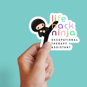 May include: A sticker featuring a cartoon ninja in a black outfit kicking. The sticker has the words "life hack ninja" in colorful letters, with "occupational therapy assistant" below. The sticker is held by a hand against a teal background.