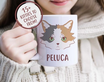 Könnte beinhalten: Eine weiße Keramiktasse mit einer Cartoon-Illustration einer dreifarbigen Katze mit grünen Augen. Die Tasse hat den Text "PELUCA" unten und den Text "15+ KITTIES TO CHOOSE FROM!" in einem Kreis auf der Seite aufgedruckt.