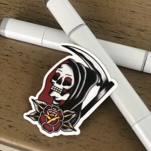 May include: A white sticker with a black and white illustration of a grim reaper holding a scythe with a red rose and green leaves below the reaper's head.