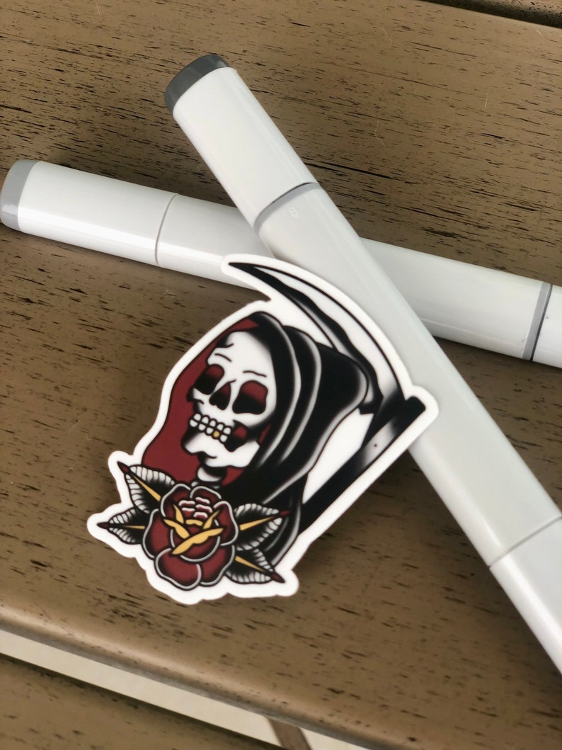 May include: A white sticker with a black and white illustration of a grim reaper holding a scythe with a red rose and green leaves below the reaper's head.