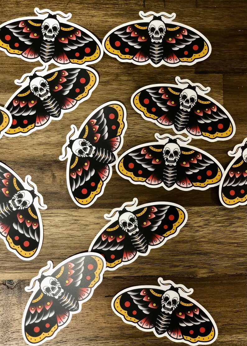 Puede incluir: Un conjunto de diez pegatinas de polilla negras y blancas con acentos rojos y amarillos. Cada polilla tiene un dise&ntilde;o de calavera en su cuerpo.