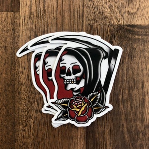 May include: A sticker featuring a traditional tattoo style image of the Grim Reaper holding a scythe with a red rose and green leaves below. The Reaper is wearing a black hooded robe and has a white skull with a red nose.
