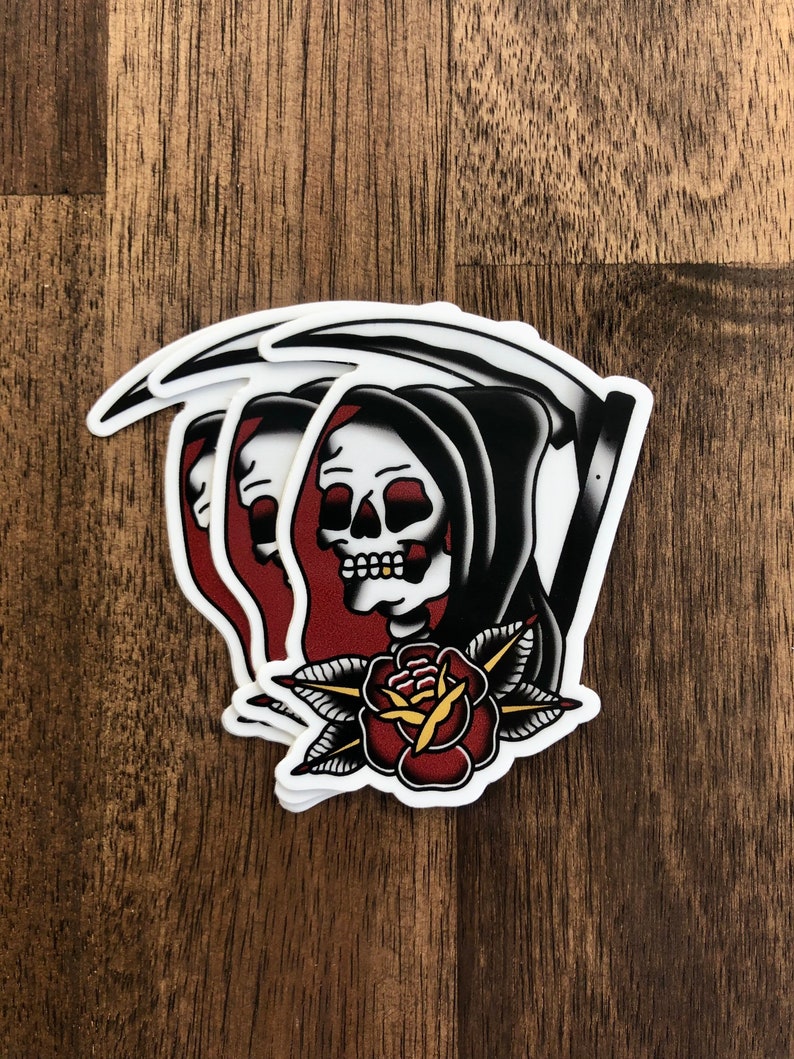 May include: A sticker featuring a traditional tattoo style image of the Grim Reaper holding a scythe with a red rose and green leaves below. The Reaper is wearing a black hooded robe and has a white skull with a red nose.