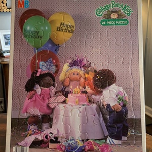 Può includere: Un puzzle di 25 pezzi con i Cabbage Patch Kids che festeggiano un compleanno. Il puzzle mostra quattro bambole Cabbage Patch Kids, una torta di compleanno con candele e coriandoli colorati. Il puzzle è progettato per bambini dai 3 ai 7 anni.