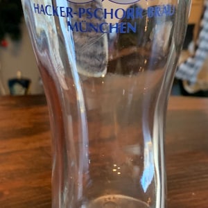 May include: A clear glass beer stein with a blue and red logo that says "Hacker-Pschorr Brau Munchen". The logo features two crossed axes and a star with a letter "P" inside.