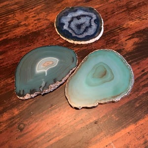 May include: Three agate coasters, one blue and two green, with natural patterns and edges.