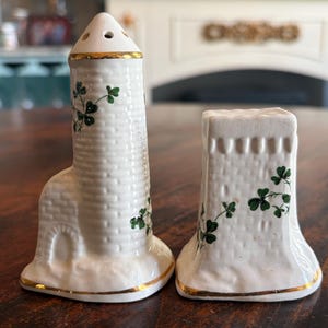 May include: A set of three ceramic mugs with a speckled, matte finish. The mugs are in shades of cream, light gray, and dark gray. Each mug has a simple, minimalist design and a rounded handle. The mugs are likely for coffee or tea.