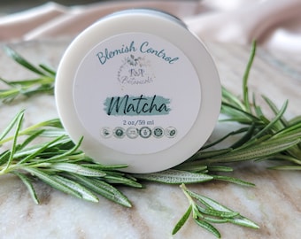 May include: A white jar with a green and white label that reads "Blemish Control R&P Botanicals Matcha 2 oz/59 ml". The jar is surrounded by sprigs of rosemary.