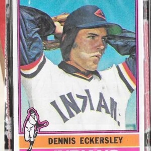 Puede incluir: Una tarjeta de b&eacute;isbol con Dennis Eckersley, un lanzador de los Indios de Cleveland. La tarjeta es del set de tarjetas de b&eacute;isbol Topps de 1977. La tarjeta presenta una foto a color de Eckersley con su uniforme de los Indios, con el logotipo del equipo en su gorra. La tarjeta tambi&eacute;n incluye el nombre, la posici&oacute;n y el nombre del equipo de Eckersley.