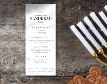 May include: A white card with a blue and white design featuring a Hanukkah dinner menu. The menu includes appetizers, entrees, desserts, and drinks. The card is on a wooden surface with a menorah and gelt coins.