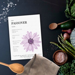 Può includere: Un menu di Seder di Pasqua stampabile con una grafica di fiori viola. Il menu elenca antipasti, piatti principali, dessert e bevande. Il testo include la citazione "In ogni generazione, una persona deve vedersi come se avesse lasciato personalmente l'Egitto."