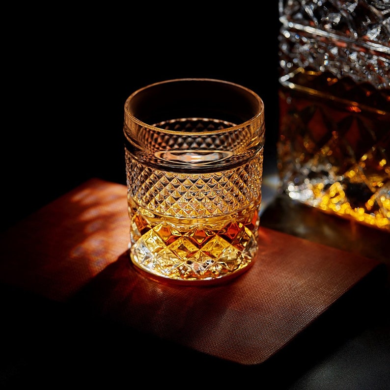 May include: A clear glass with a diamond pattern is filled with amber-colored liquid. The glass sits on a brown surface.