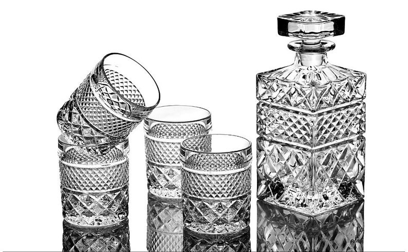May include: A set of four clear glass tumblers and a clear glass decanter with a diamond pattern. The decanter has a stopper.