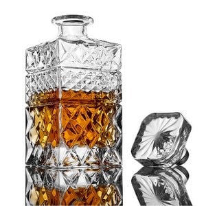 May include: A clear glass decanter with a square body and a diamond-shaped pattern. The decanter has a stopper with a star-shaped design.