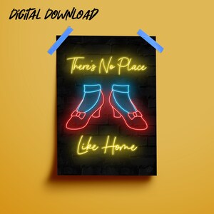 Op de afbeelding: Een digitale download van een afdrukbare poster met een neon-ontwerp. Het bord zegt "There's No Place Like Home" met een paar rode robijnenschoenen in het midden. De achtergrond is een zwarte bakstenen muur.