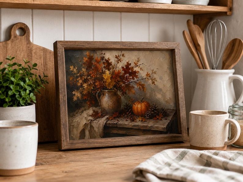 May include: A framed rectangular wall art print featuring an oil painting of a rustic ceramic pitcher filled with autumn leaves, a small orange pumpkin, and pinecones resting on a wooden table surface with a draped fabric cloth underneath.