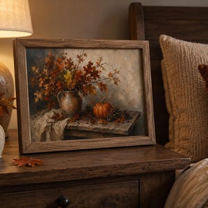 May include: A framed oil painting depicting a still life scene with a ceramic pitcher filled with autumn leaves, a small orange pumpkin, and pinecones resting on a wooden table, rendered in warm shades of brown, orange, and cream.