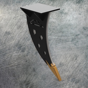 May include: A black and gold decorative stand with a gray top. The stand has a curved design with geometric cutouts and a gold-colored tip. The top is a square shape.