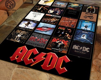 May include: A black and red rug with the AC/DC logo and album covers. The rug features album covers from the band's career, including "Back in Black", "Highway to Hell", and "For Those About to Rock We Salute You".