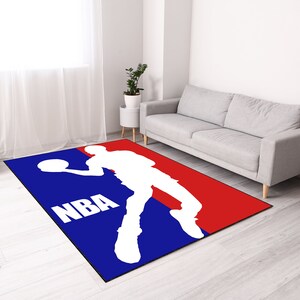 May include: A blue and red rug with the NBA logo and a basketball player silhouette. The logo says "NBA".