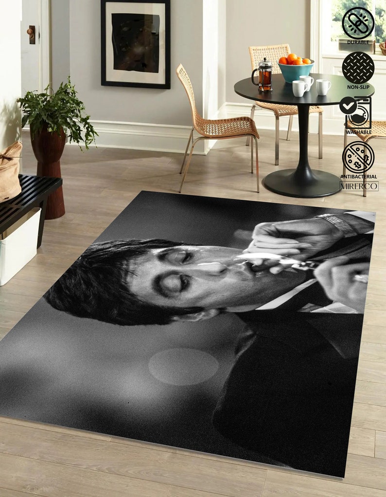 May include: Black and white rug featuring a close-up of a man's face. The man is smoking a cigarette and has a serious expression. The rug is made of a soft, durable material and is perfect for adding a touch of style to any room.