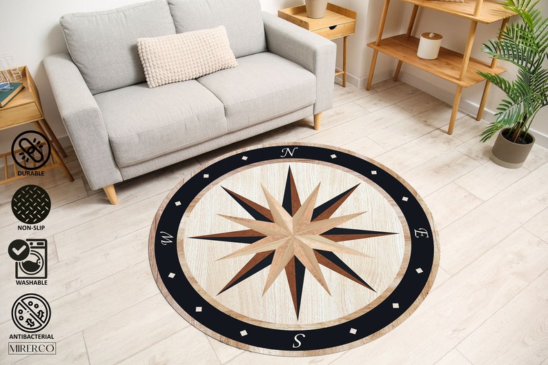 May include: A round rug with a compass design in shades of brown, black, and white. The compass features a starburst design with the letters N, S, E, and W around the edge.