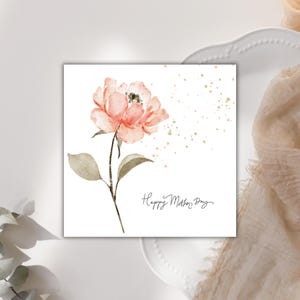 Square Mother’s Day card with watercolor blush pink flower and gold speckles on soft neutral styled background.