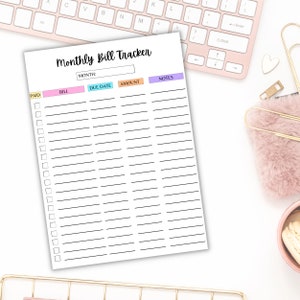 Monthly bill tracker sheet with colorful headers and checkboxes displayed on a soft pink desk with a keyboard, pen, and cozy accessories.