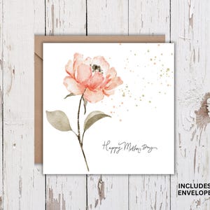 Square Mother’s Day card with watercolor pink flower and gold accents shown with kraft envelope on white rustic wood background.
